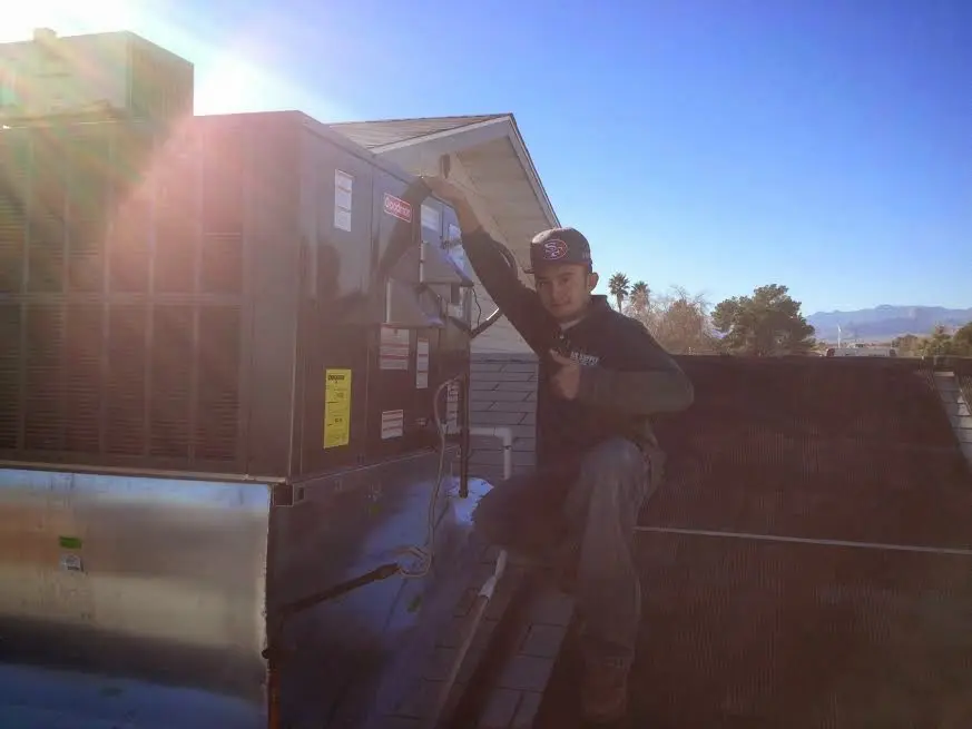 HVAC technician performing HVAC Inspection on a rooftop unit in Gallup