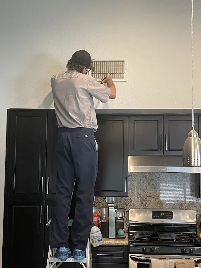 Technician inspecting an air vent during HVAC service in Gallup